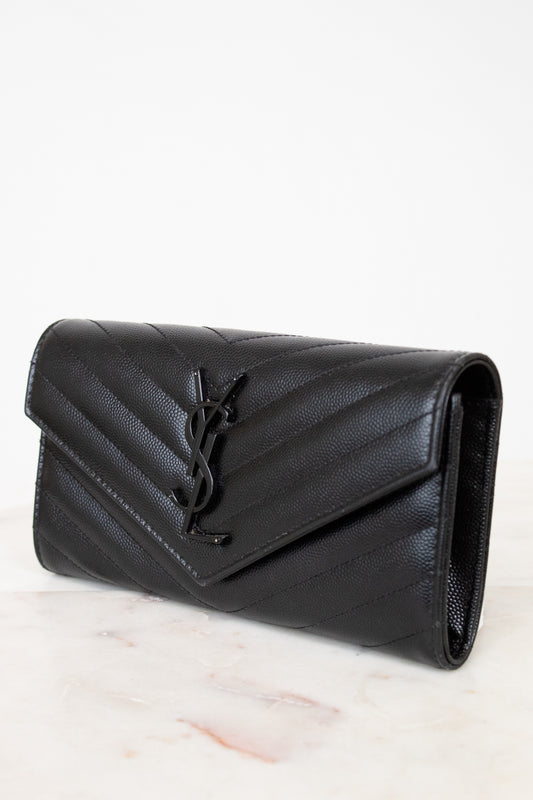 Black quilted wallet bag on a light marble surface