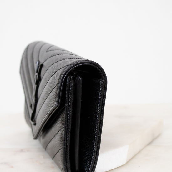 Black quilted wallet bag on a white marble surface