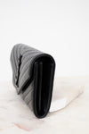 Black quilted wallet bag on a white marble surface
