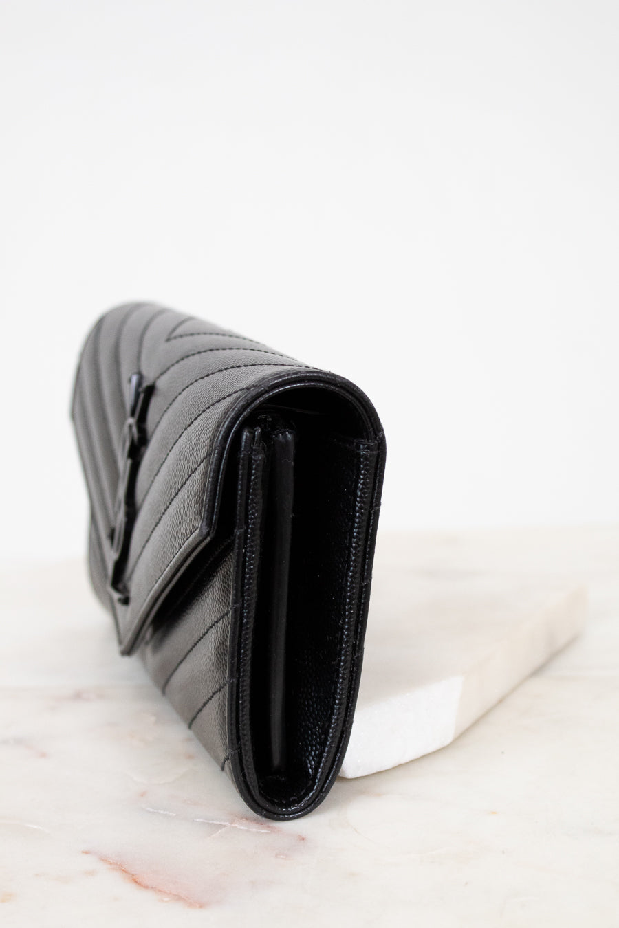 Black quilted wallet bag on a white marble surface