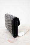 Black quilted clutch bag on a light marble surface
