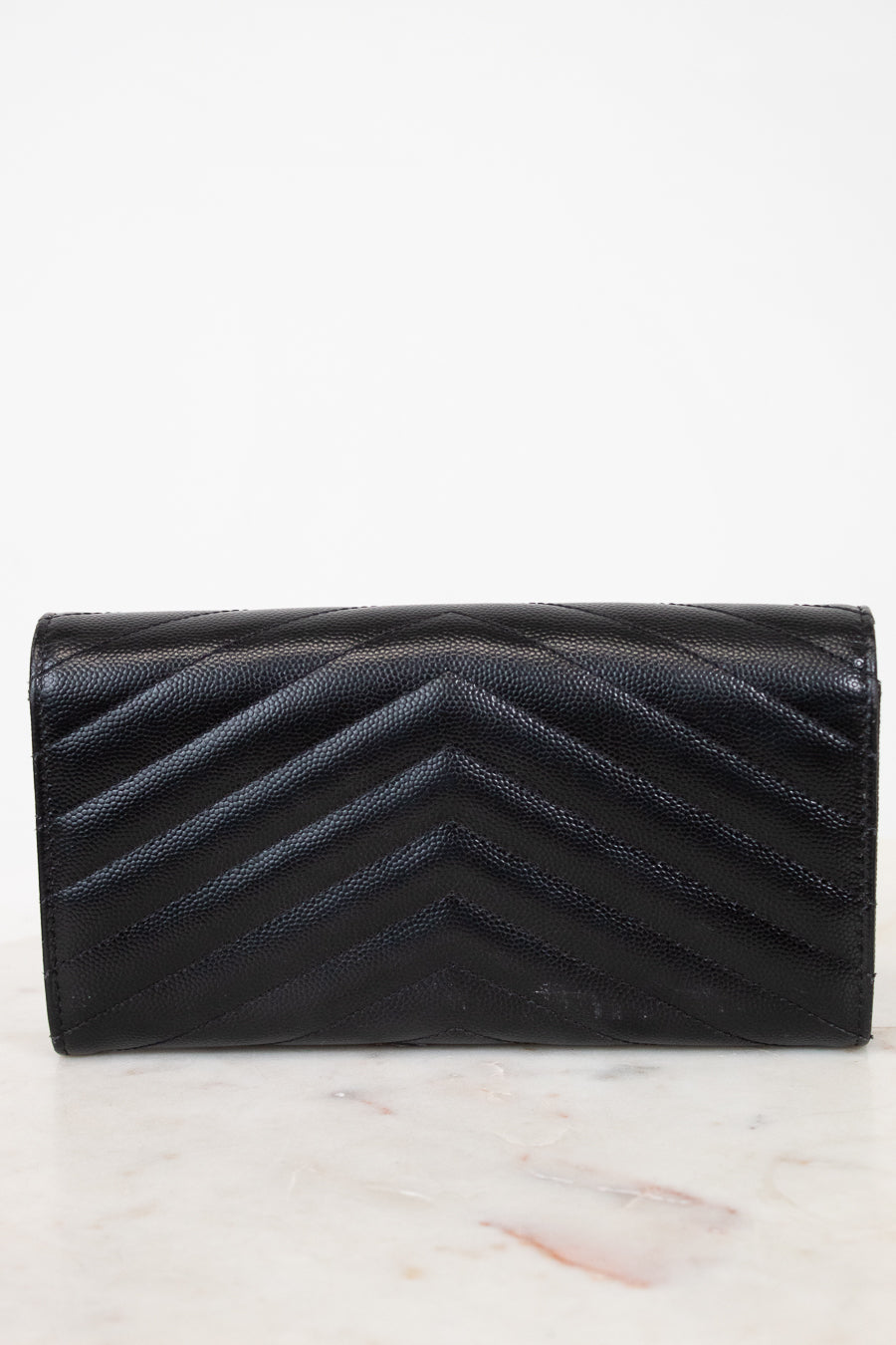 Black quilted wallet on a light marble background