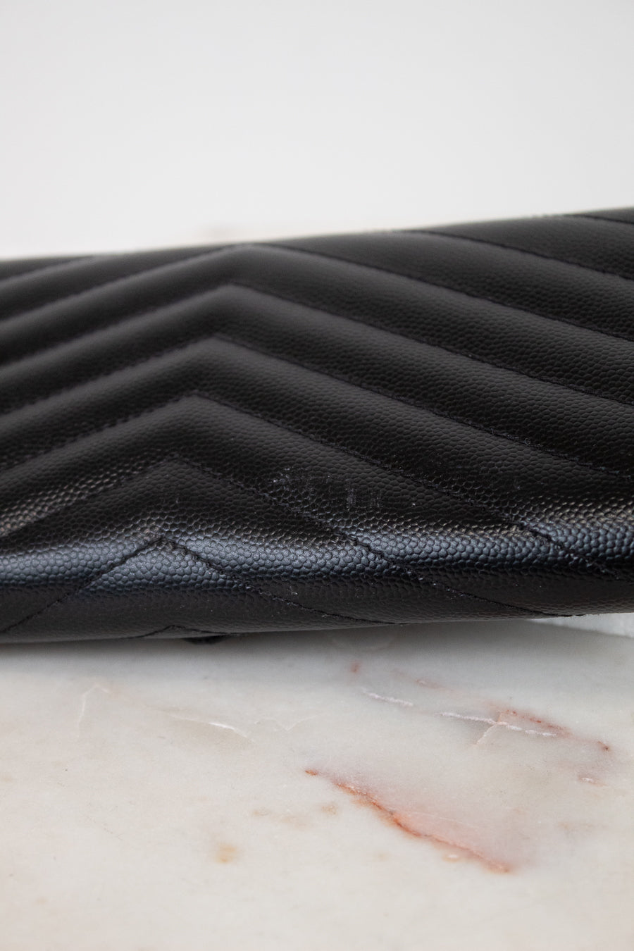 Black quilted leather wallet on a marble surface