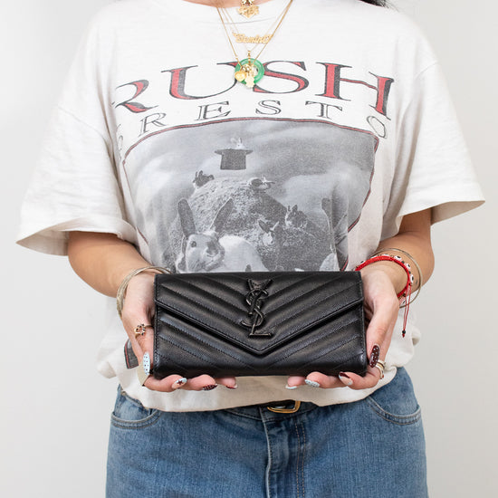 Person holding a black wallet with a graphic t-shirt and jeans