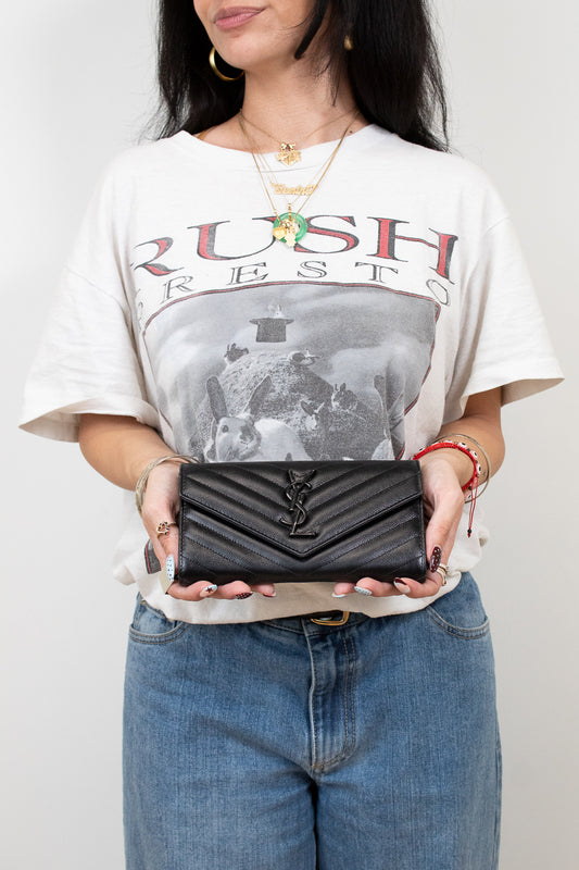Person holding a black wallet with a graphic t-shirt and jeans