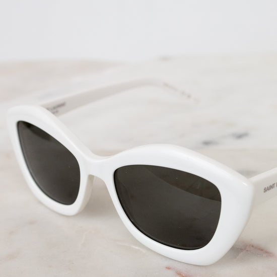 White sunglasses with dark lenses on a marble surface