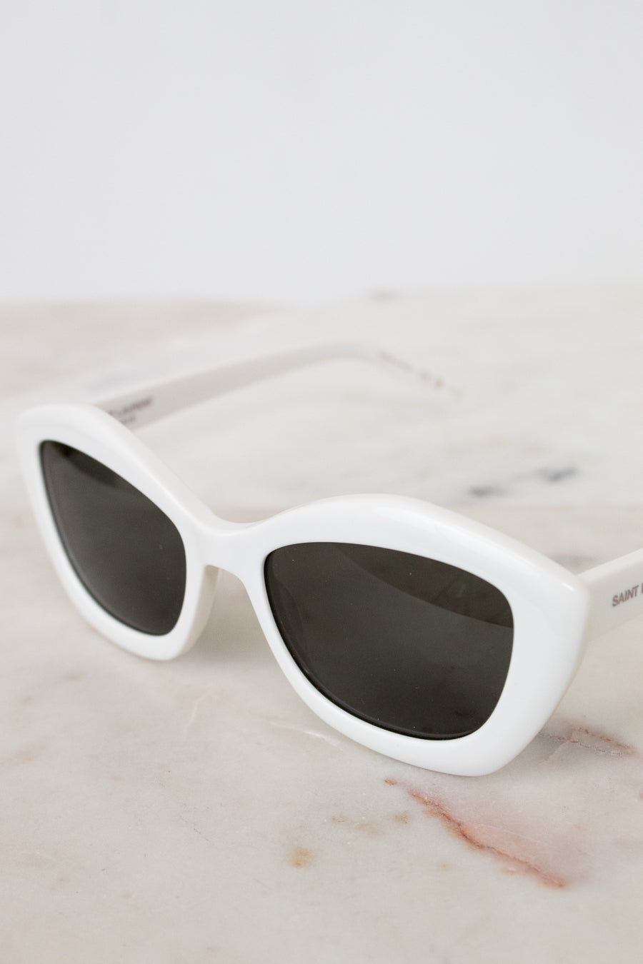 White sunglasses with dark lenses on a marble surface
