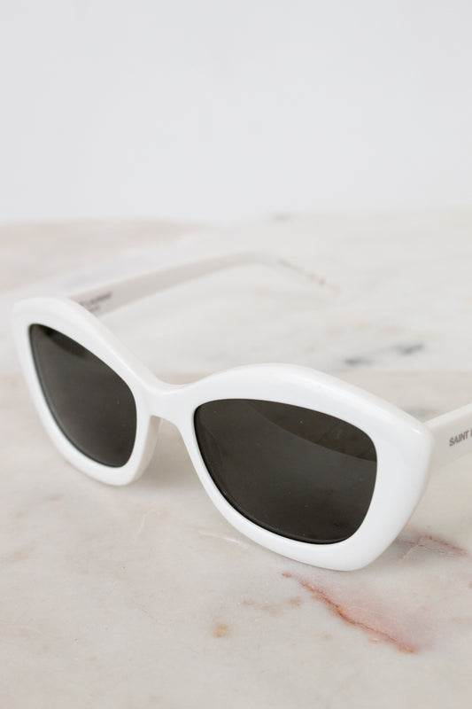 White sunglasses with dark lenses on a marble surface