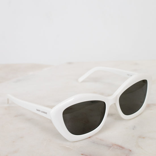 White sunglasses with dark lenses on a marble surface