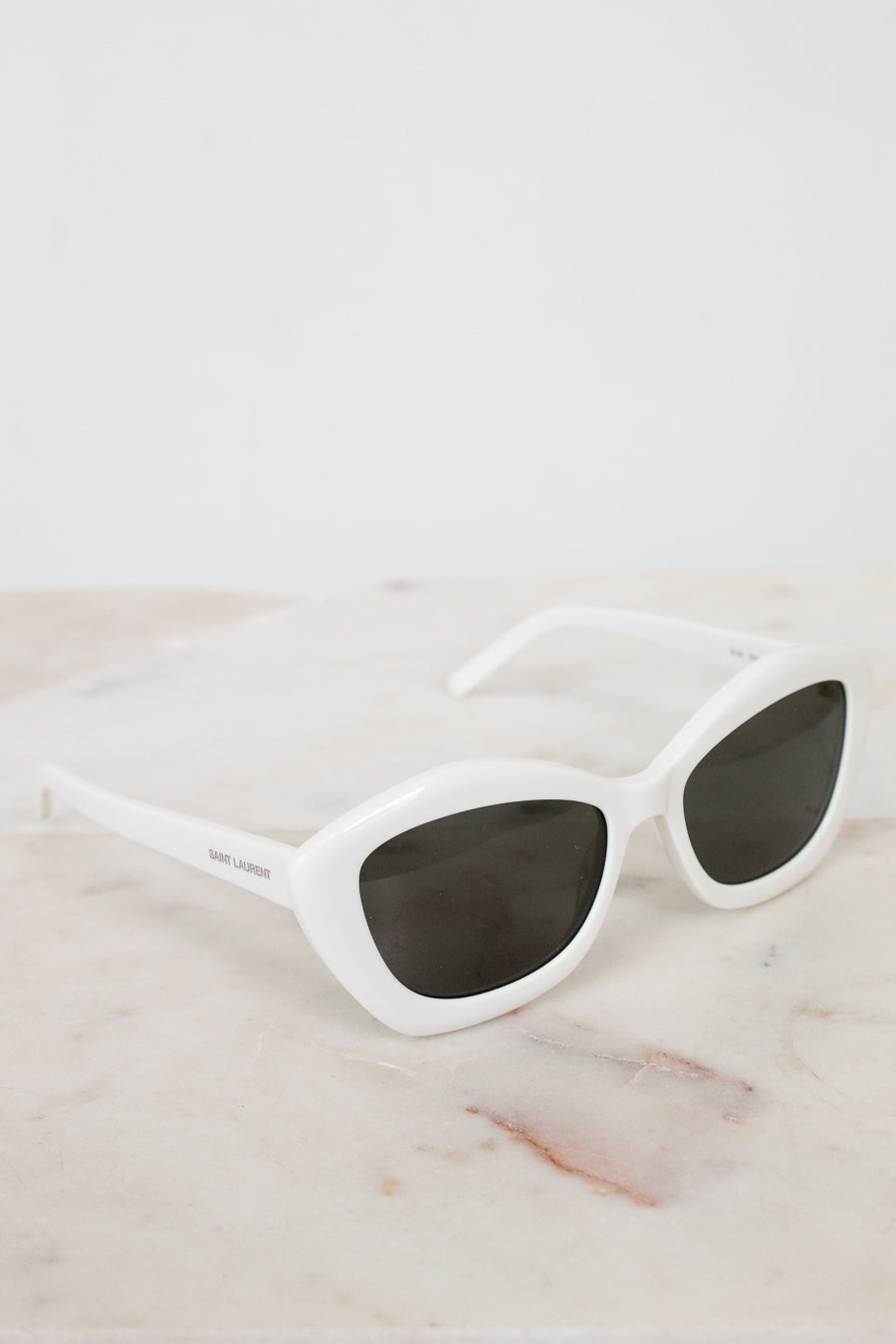 White sunglasses with dark lenses on a marble surface