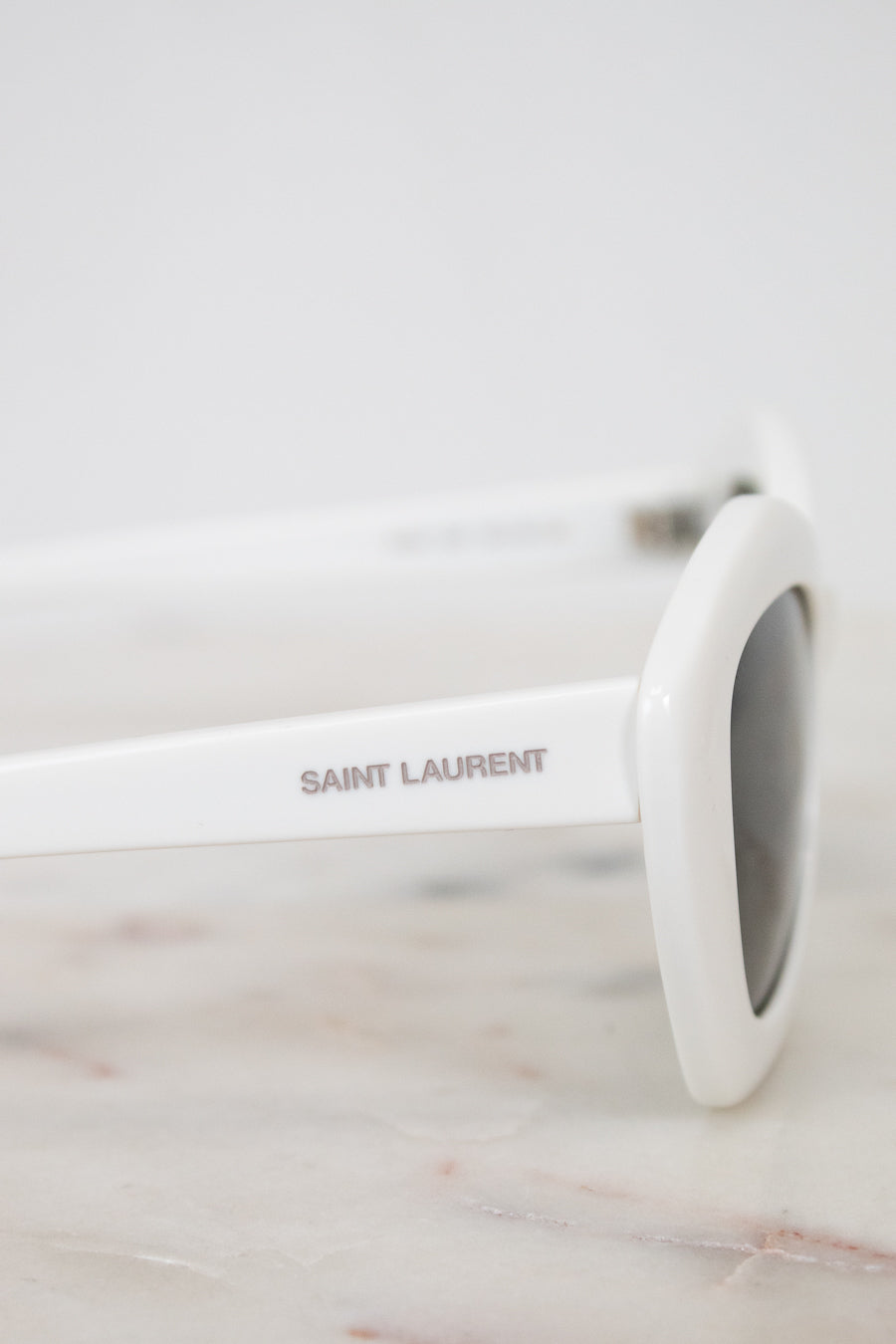 White Saint Laurent sunglasses on a marble surface