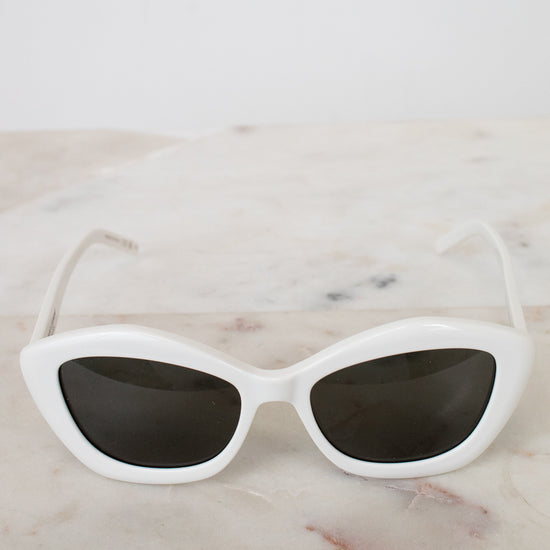 White cat-eye sunglasses on a marble surface