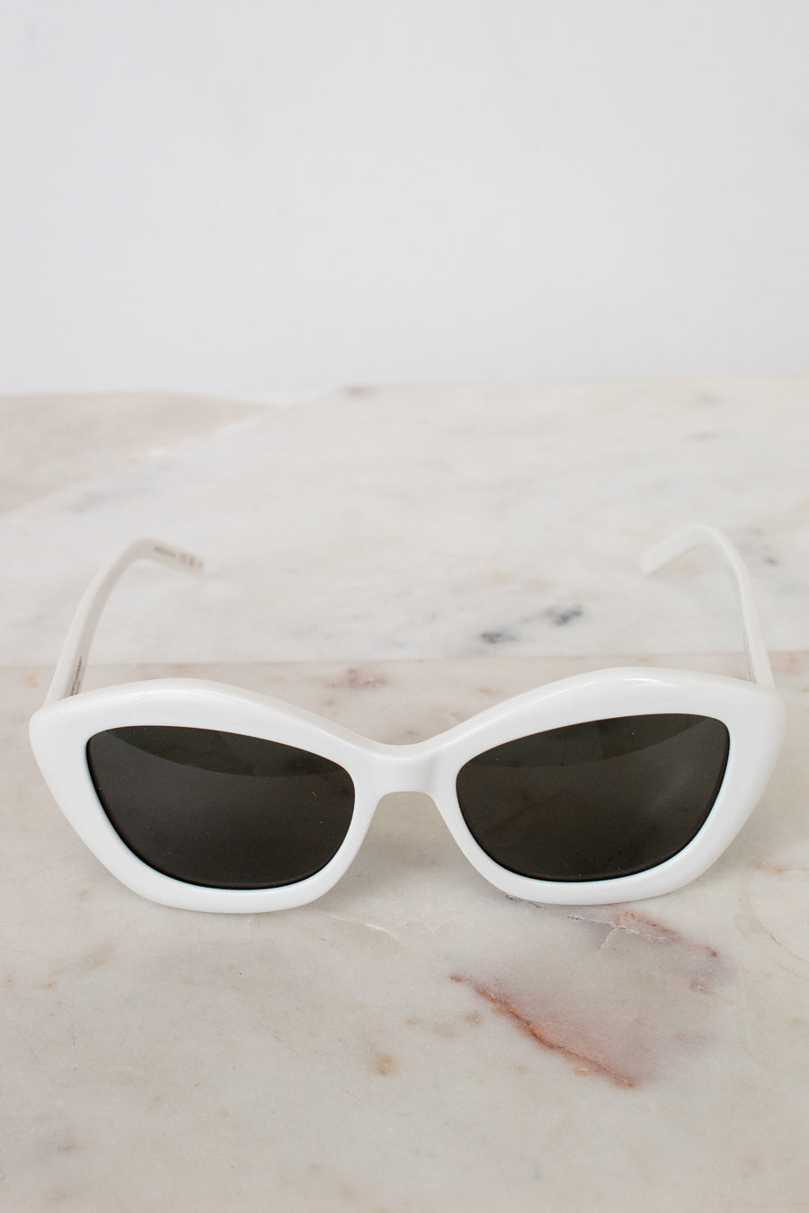 White cat-eye sunglasses on a marble surface