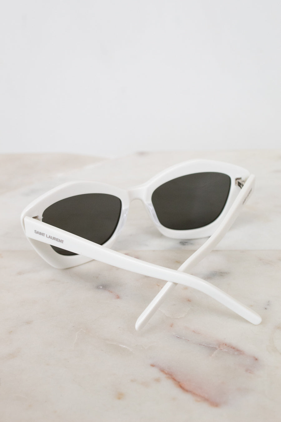White sunglasses with black lenses on a marble surface
