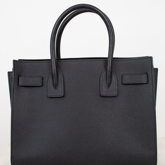 A black pebbled leather handbag with double top handles, shown against a clean white background.
