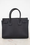 A black pebbled leather handbag with double top handles, shown against a clean white background.