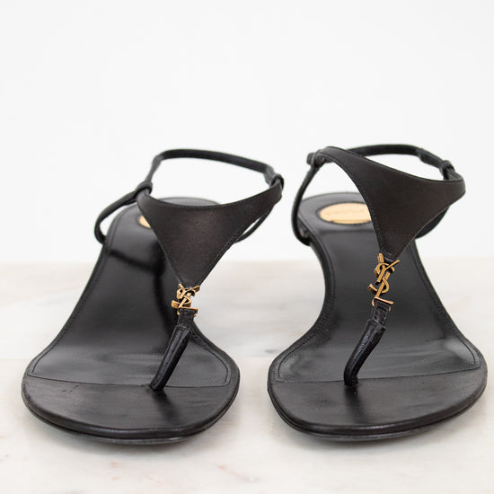 Pair of black sandals with a "YSL" brand logo on a light background