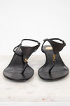 Pair of black sandals with a "YSL" brand logo on a light background