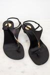 Pair of black sandals with gold accents on a white marble surface