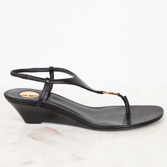 Black wedge sandal on a white marble surface