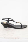 Black wedge sandal on a white marble surface