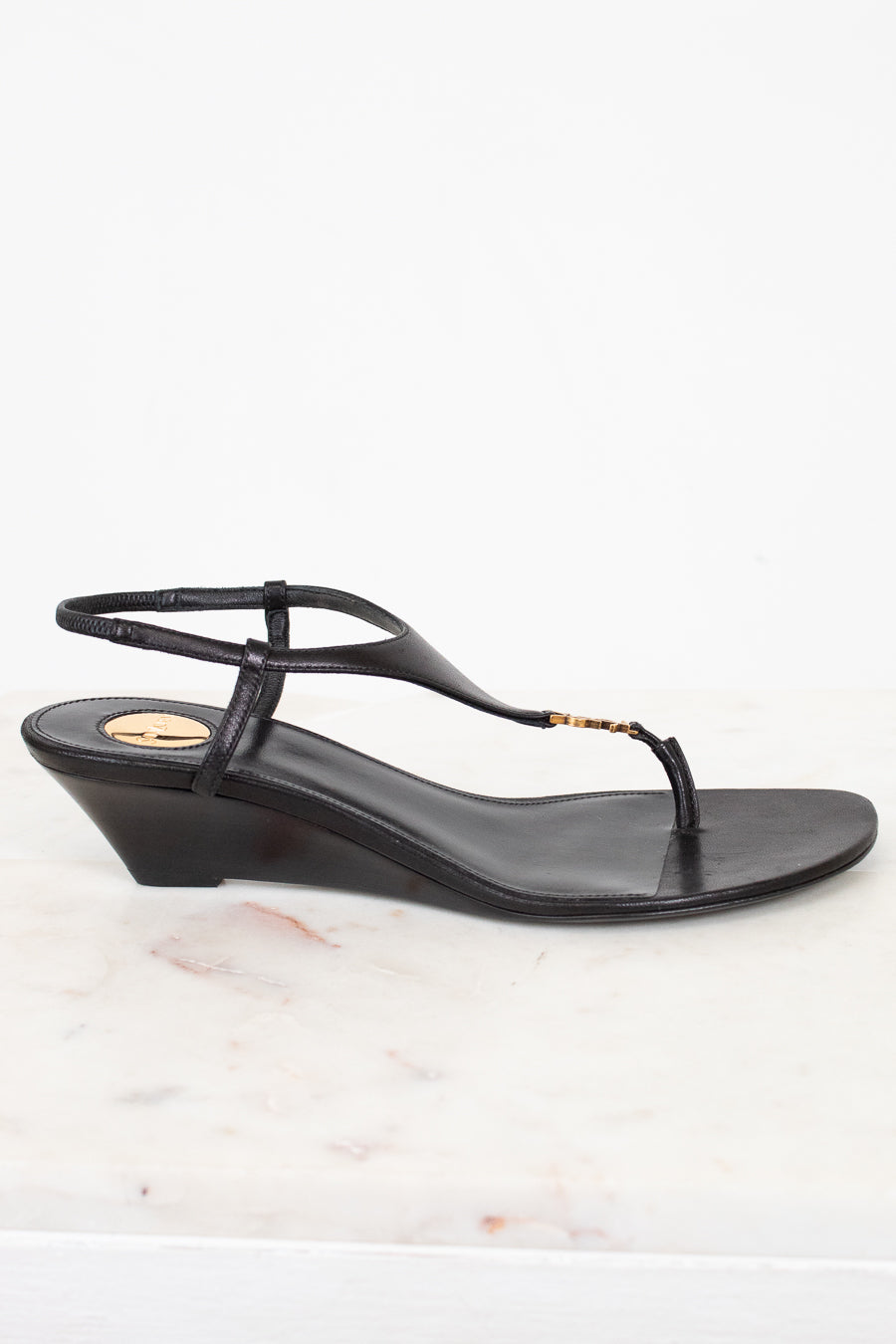 Black wedge sandal on a white marble surface