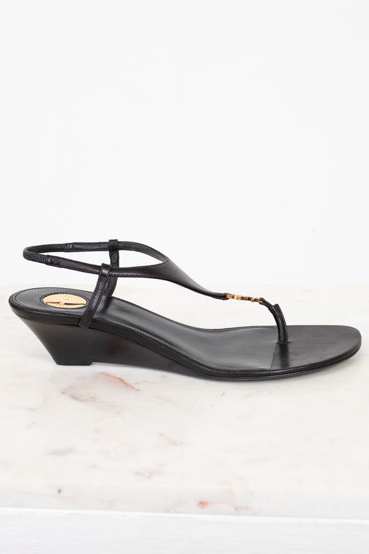 Black wedge sandal on a white marble surface