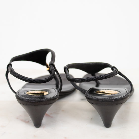 Black wedge-heeled shoes with thin straps on a light background