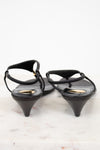 Black wedge-heeled shoes with thin straps on a light background