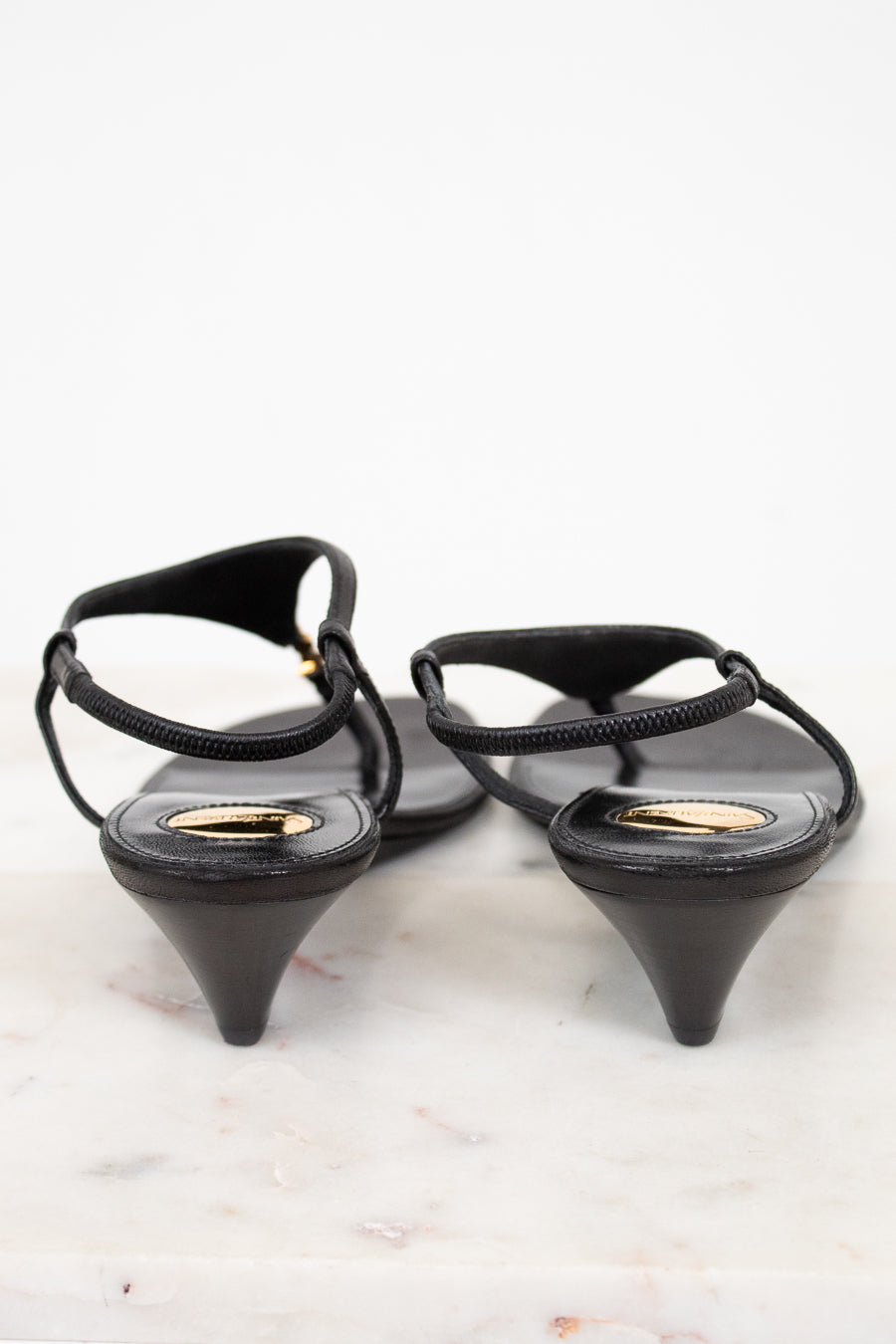 Black wedge-heeled shoes with thin straps on a light background