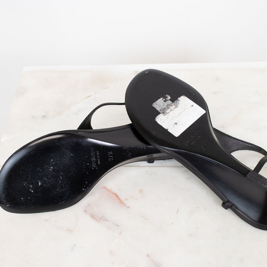 Black heeled shoes with black soles on a marble surface