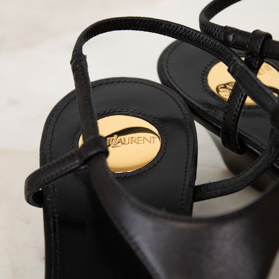 Black sandals with a brand logo on a light background
