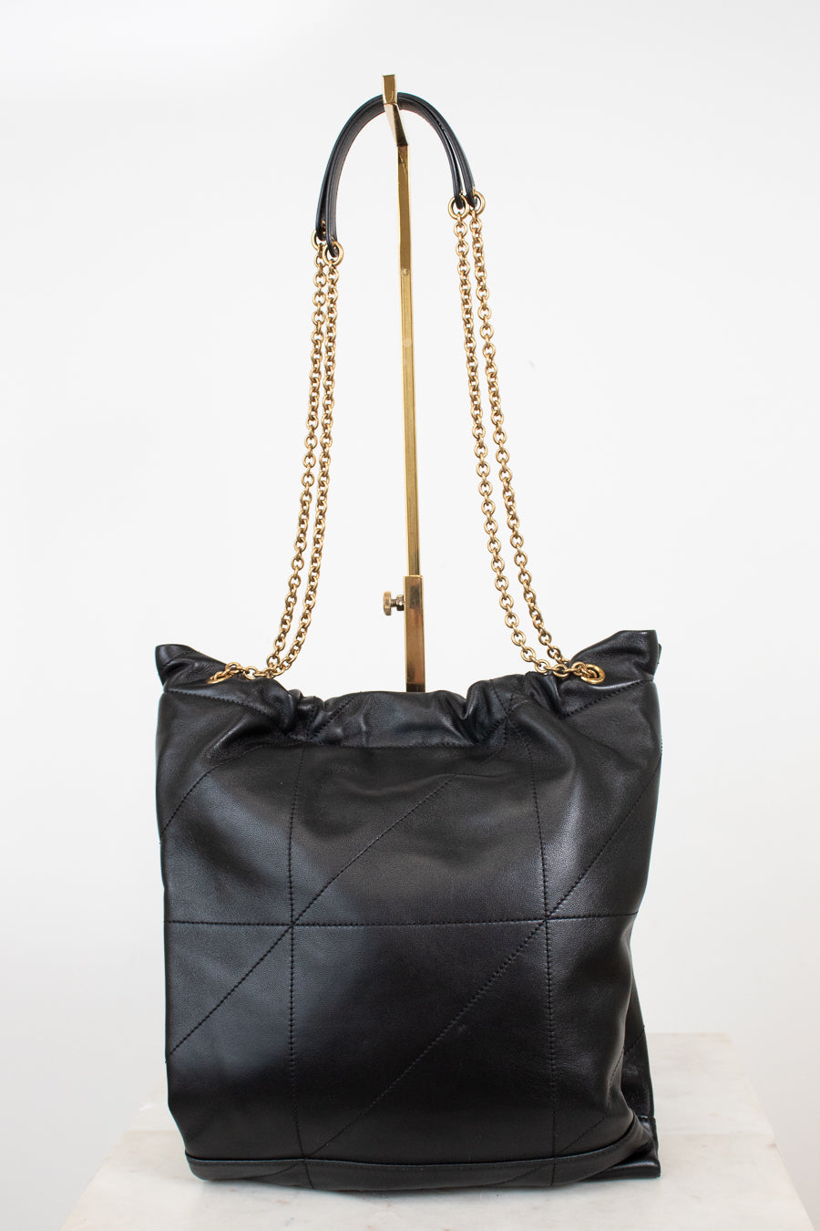 A black leather slouchy shoulder bag with a gold-tone chain strap, displayed on a white studio background.