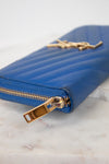 Blue wallet with gold zipper and logo on a marble surface