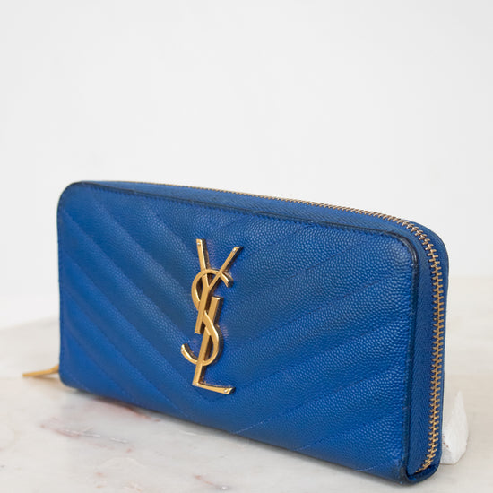 Blue wallet with gold logo on a marble surface