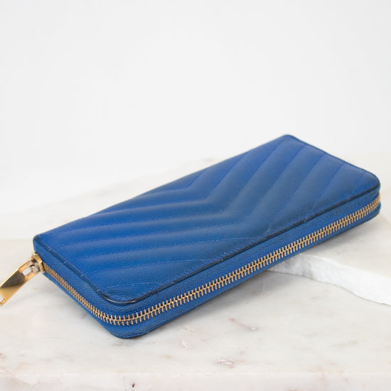 Blue wallet with gold zipper on a white marble surface