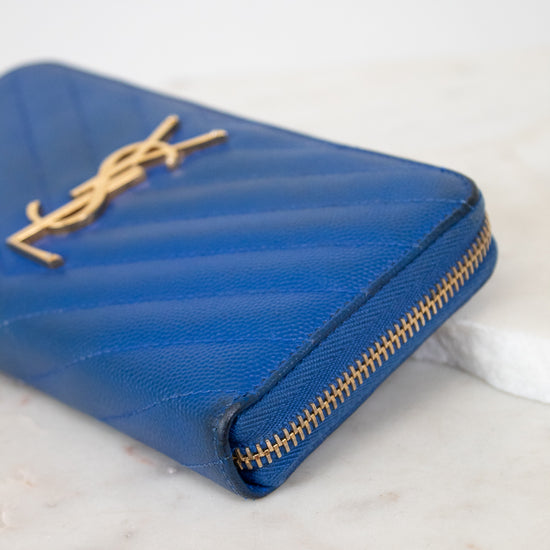 Blue wallet with gold zipper on a marble surface