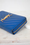 Blue wallet with gold zipper on a marble surface