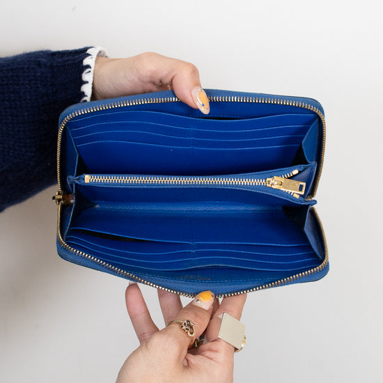 Blue wallet held open by a person against a white background