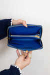 Blue wallet held open by a person against a white background