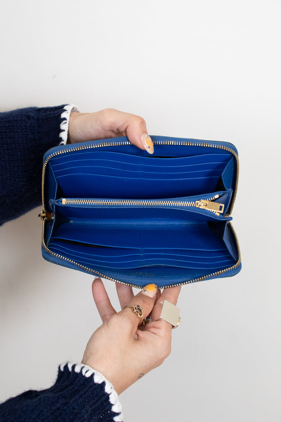 Blue wallet held open by a person against a white background
