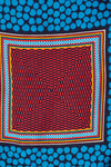 A square scarf with a bold geometric pattern, featuring a central red, black, and blue abstract checkerboard-like grid surrounded by concentric multicolor borders, with a dark navy background patterned with bright blue dots at the top and bottom.