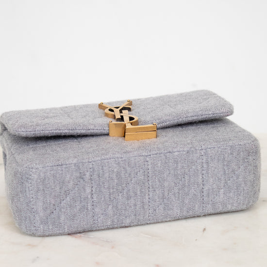 Gray YSL bag with a gold clasp on a marble surface