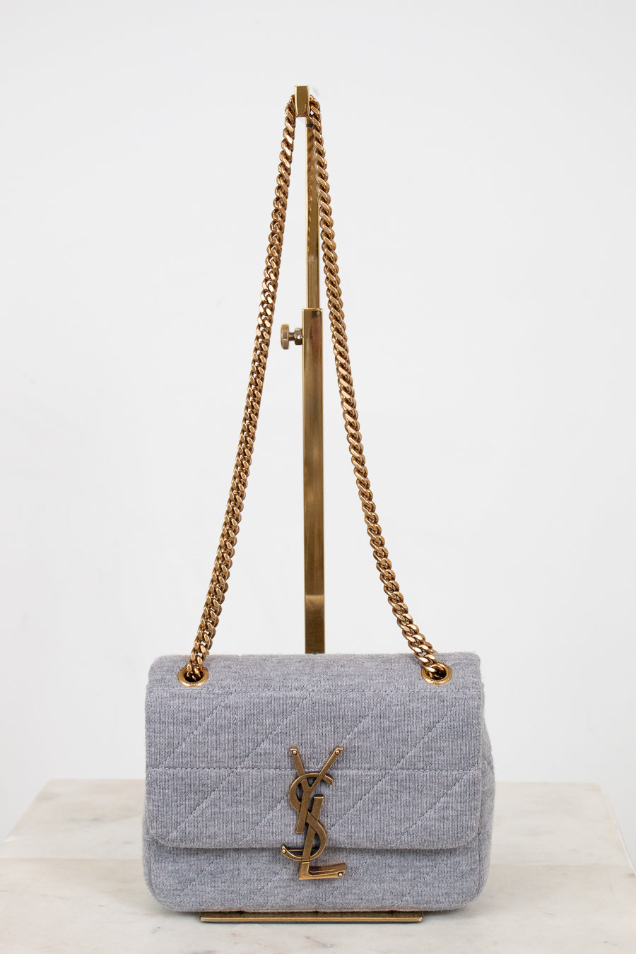 Gray quilted YSL handbag with gold chain strap on a white background