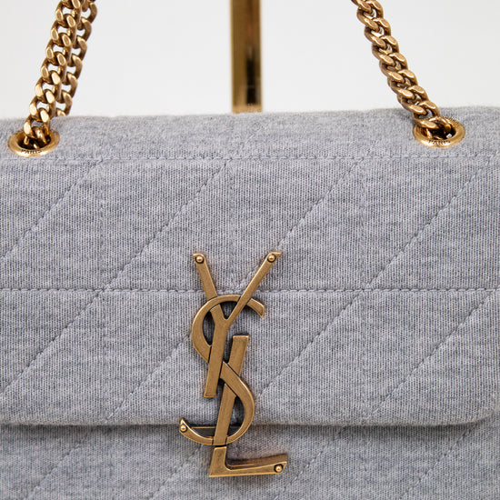 Gray quilted handbag with gold chain strap and YSL logo on a white background