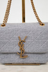 Gray quilted handbag with gold chain strap and YSL logo on a white background