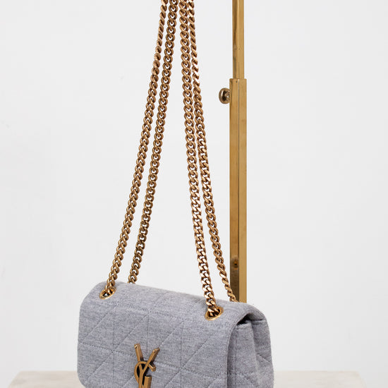 Gray quilted YSL handbag with gold chain strap on a white background