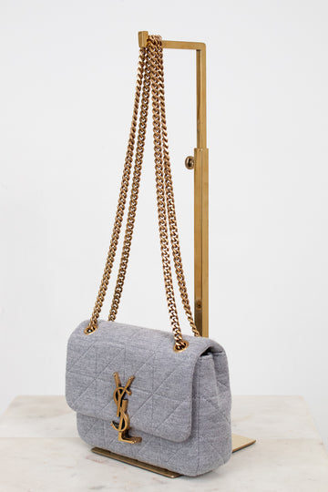 Gray quilted YSL handbag with gold chain strap on a white background