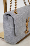 Gray textured handbag with gold chain and YSL logo on a light background
