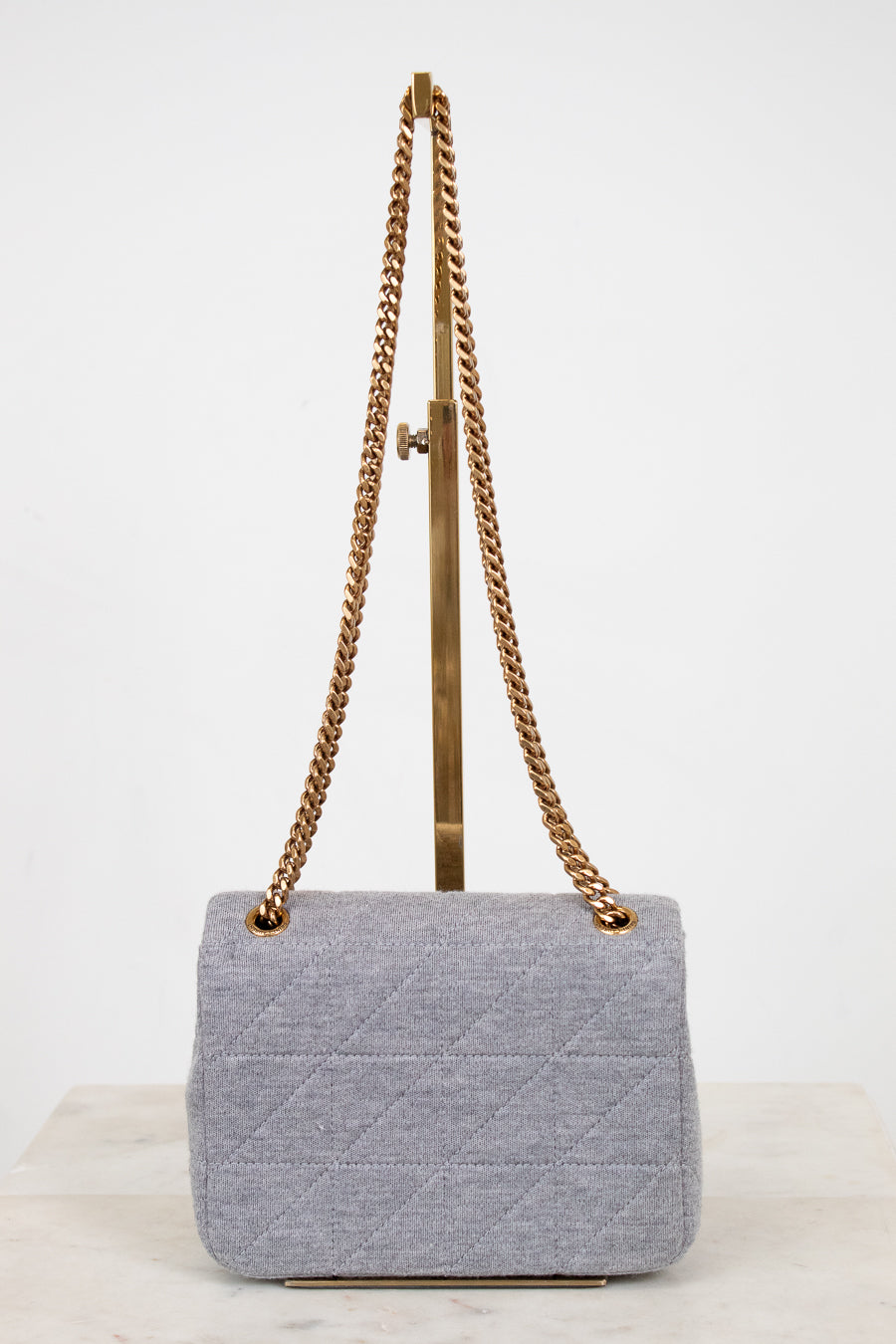 Gray quilted handbag with gold chain strap on a white background